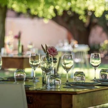 A table is set in a garden with white plates and glasses.