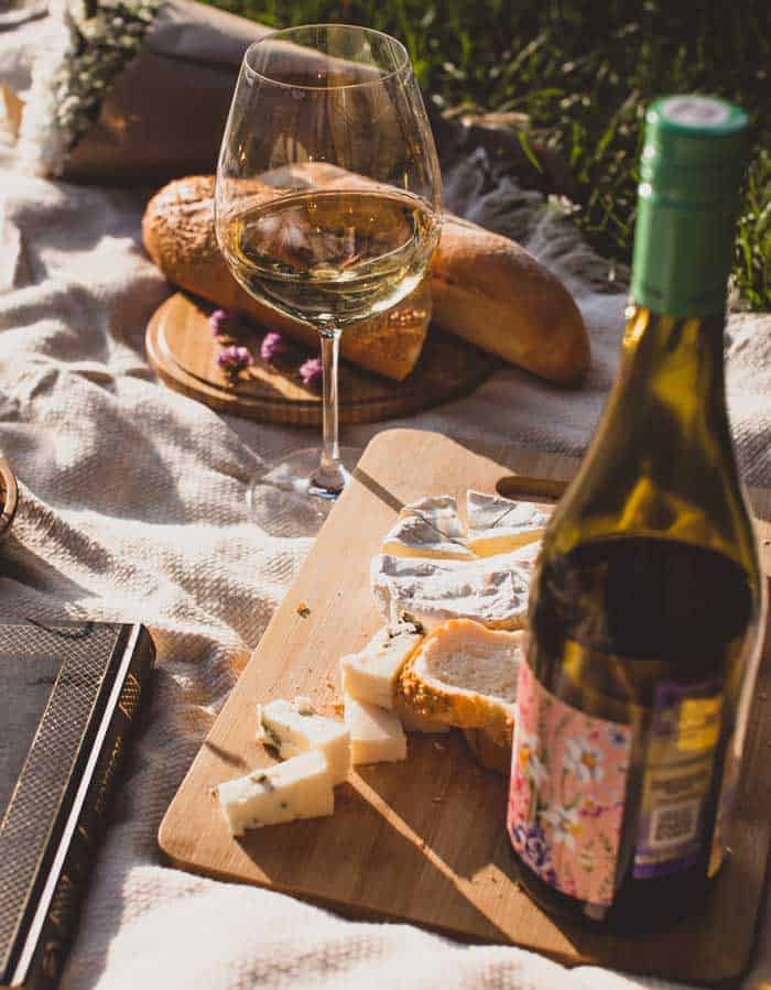 Wine and cheese on a picnic blanket. 