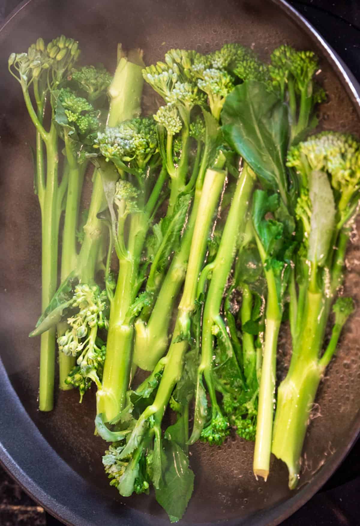 The broccoli is being blanched in a frying pan.