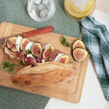 Fig and prosciutto baguette on a picnic blanket.