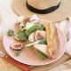 Fig and chicken baguette on a picnic blankets with straw hat.
