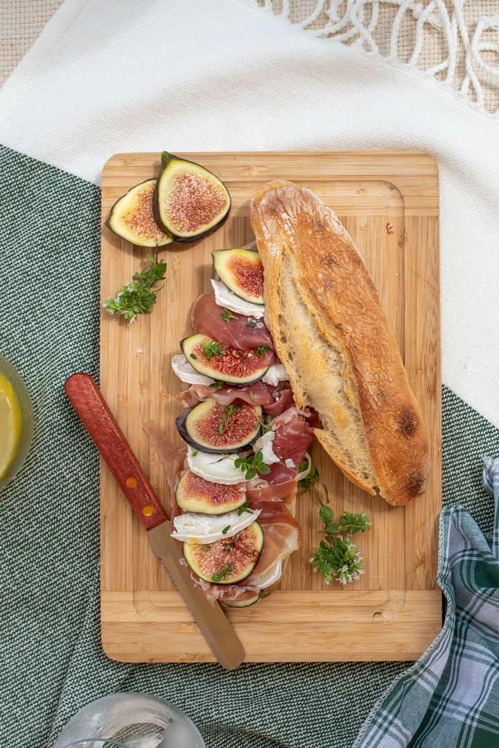 Baguette with prosciutto and figs on a wooden board. 