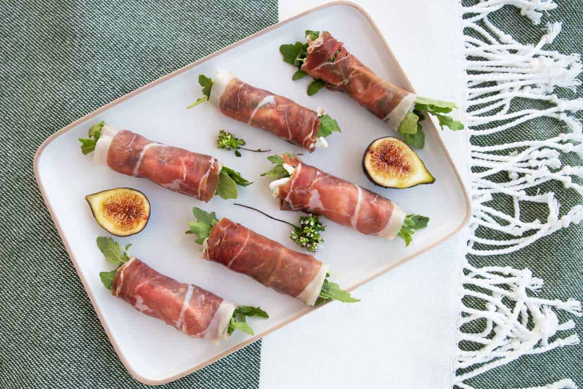 Plate of prosciutto rolls stuffed with figs and goats cheese. 