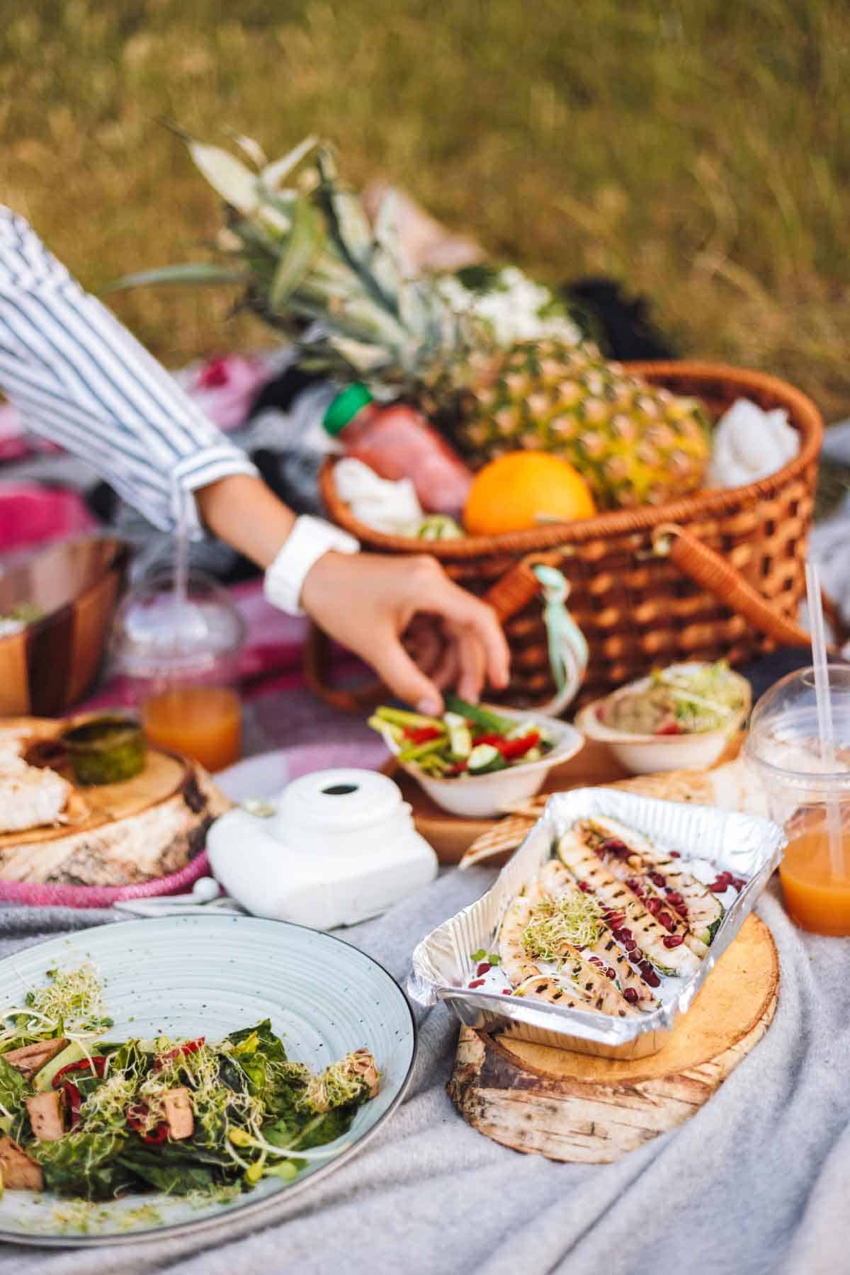 Close-up of a beautiful picnic with a variety of tasty food and fruits basket on a picnic blanket in the park.