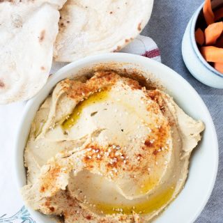 Bowl of hummus with a cup of carrot sticks