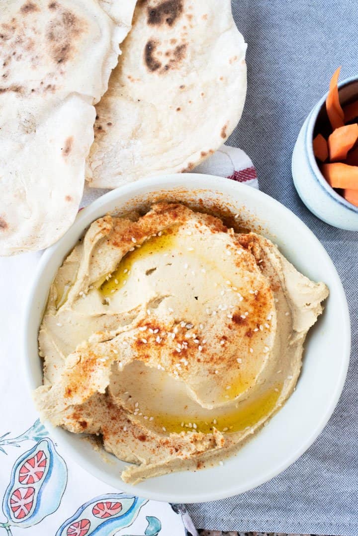 Bowl of hummus with a cup of carrot sticks