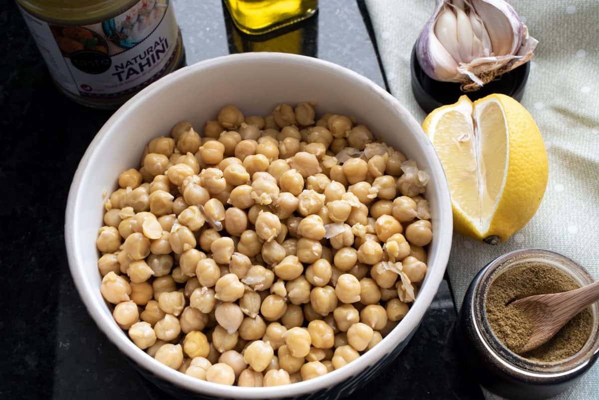 Bowl of chickpeas and ingredients for hummus. 