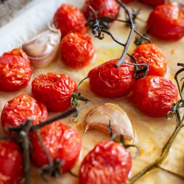 Roasted tomatoes and garlic on a baking sheet.
