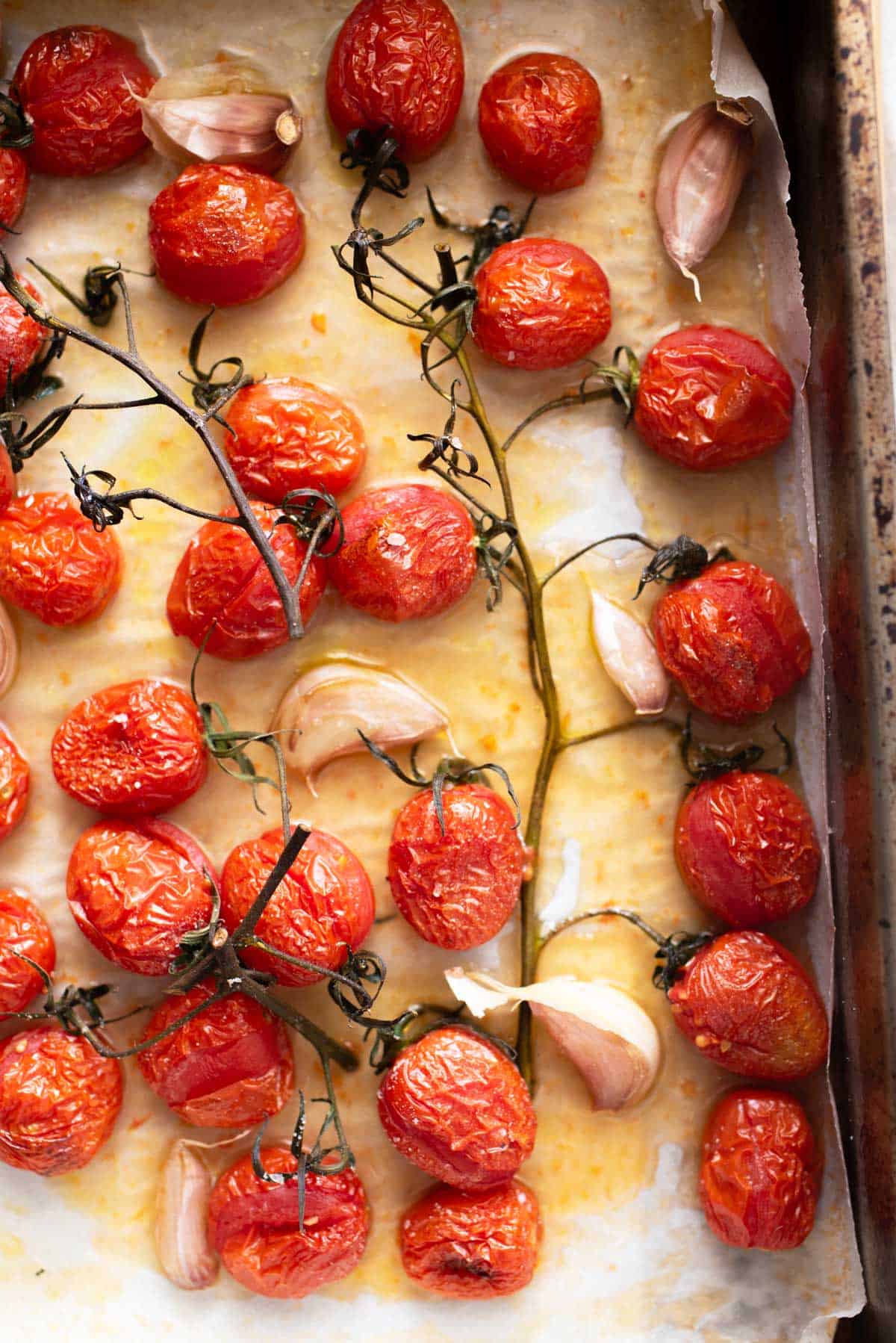 Roasted tomatoes and garlic on a baking sheet.