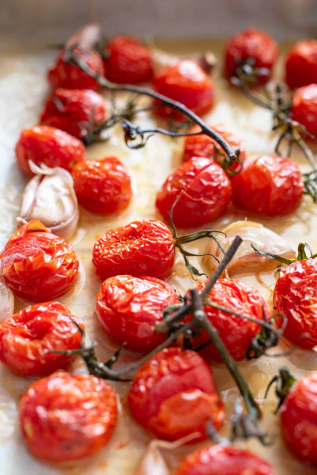 Roasted tomatoes with garlic and herbs on a baking sheet.