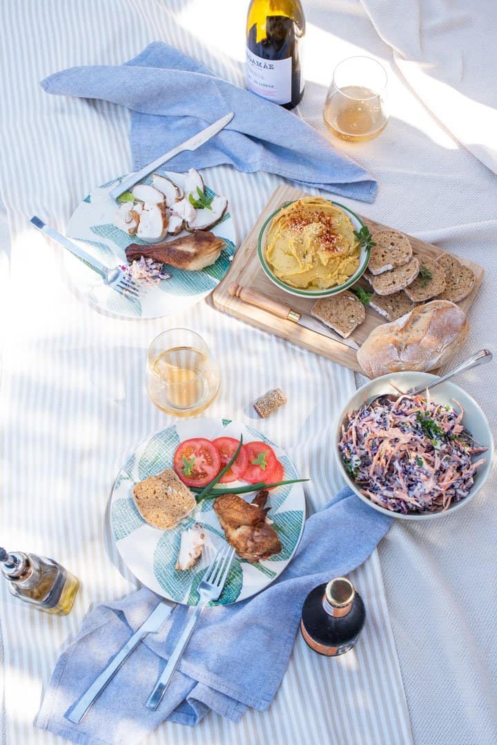 Romantic picnic layout with smoked chicken, coleslaw and hummus dip. 
