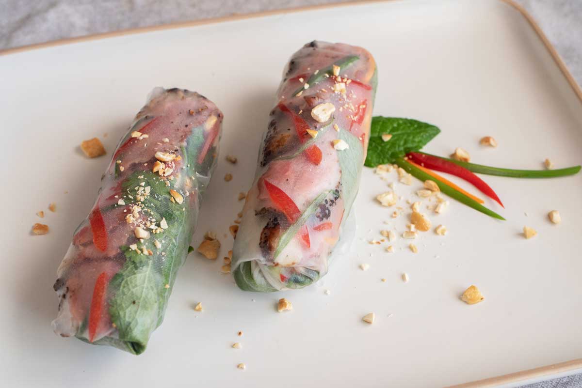 two duck rice paper rolls on a plate. 