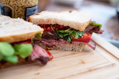 Roast beef sandwich cut in half with slow roasted tomatoes.