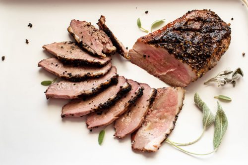 Smoked duck breast with thin slices fanned on a plate.