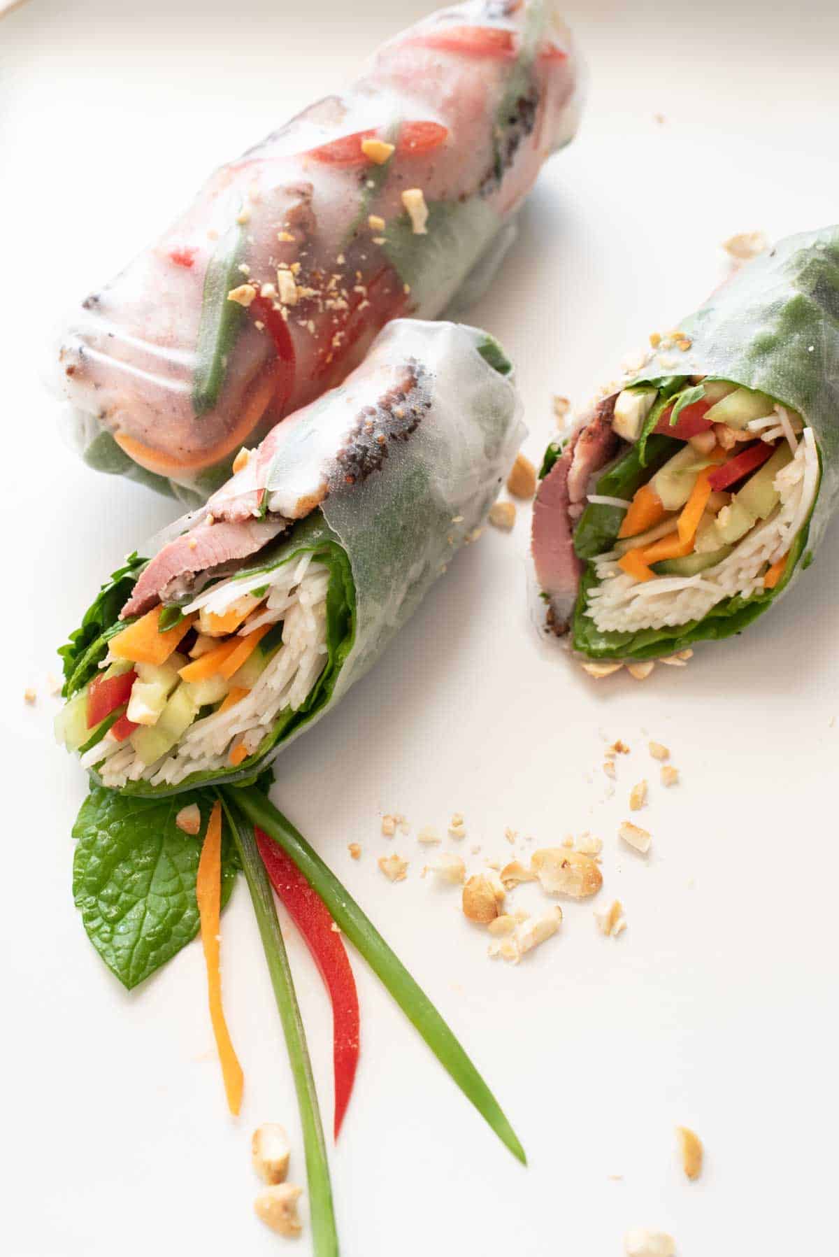 Asian style rice paper rolls cut in half on a white plate.