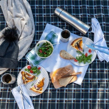 A check picnic blanket with food and drinks on it.