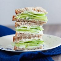 Stack of cucumber sandwich quarters on a plate.