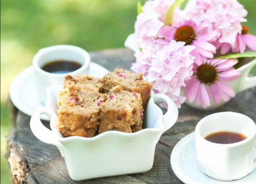 Sweet zucchini bread in a picnic scene with coffee and flowers.