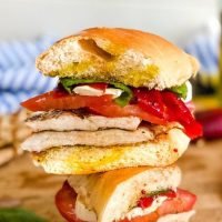 Stack of grilled chicken sandwiches with tomatoes.