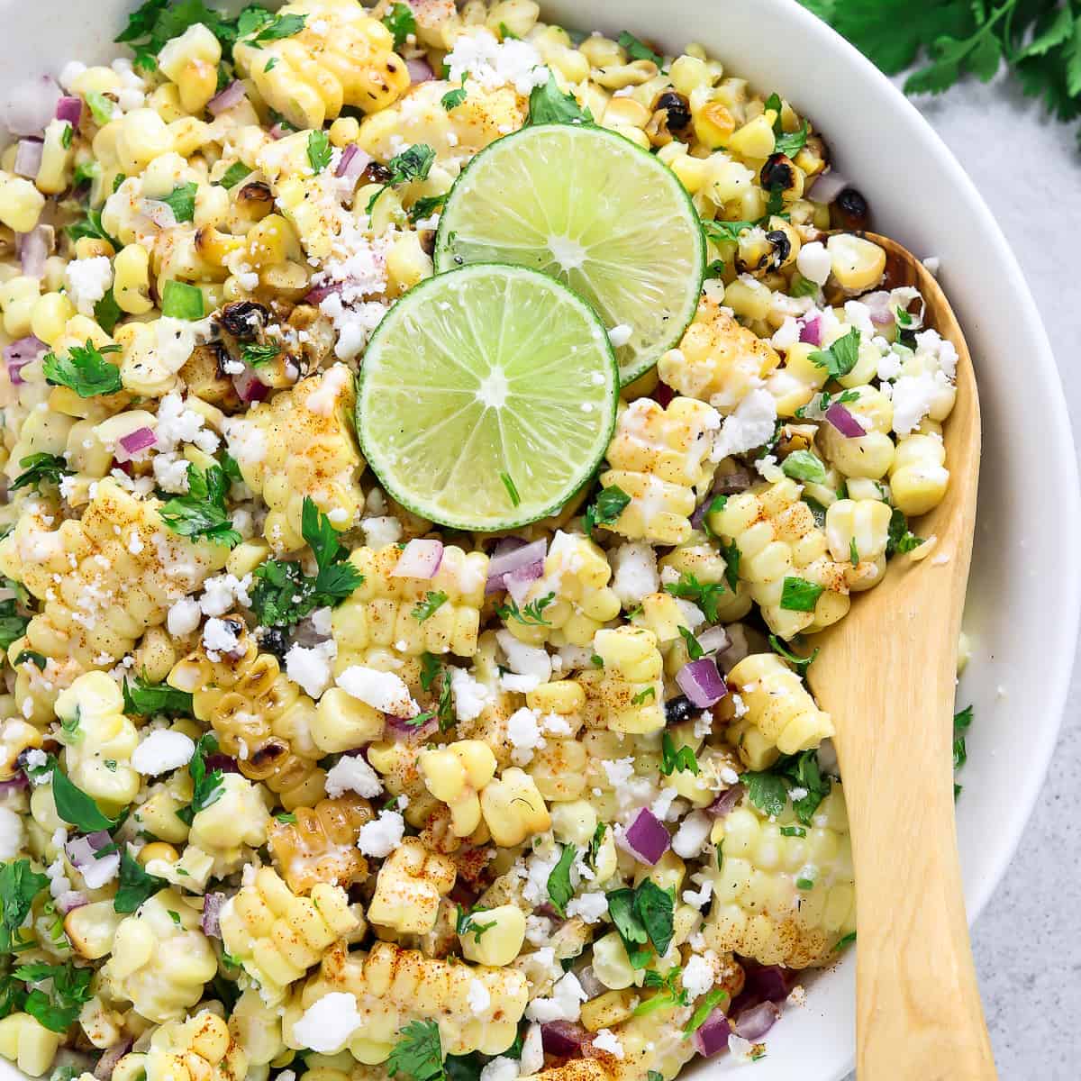 Bowl of Mexican corn salad with lime garnish.