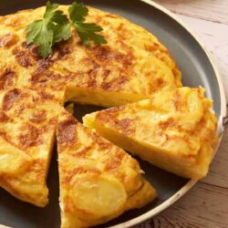 Spanish Potato Tortilla in a pan with a slice cut out.