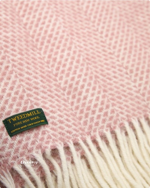 A pink and white tweed throw with fringes.