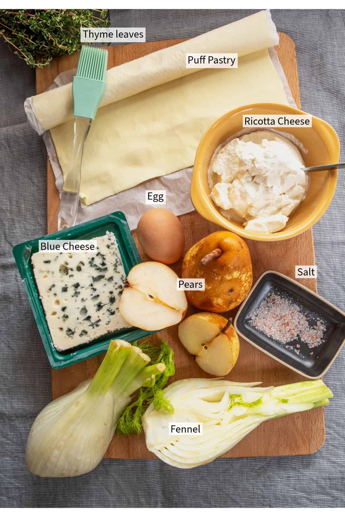 A cutting board with ingredients for a pear and blue cheese tart with fennel.