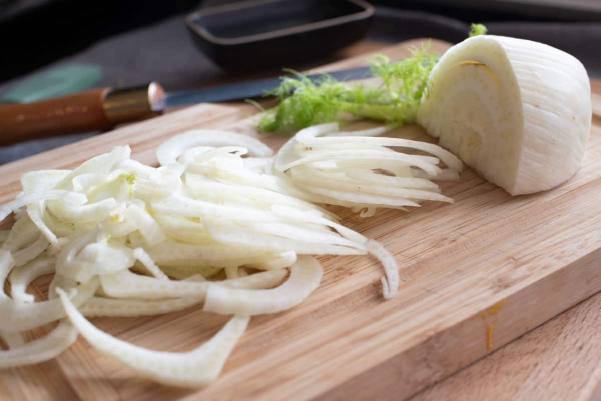 Sliced fennel on a cutting board with a knife.