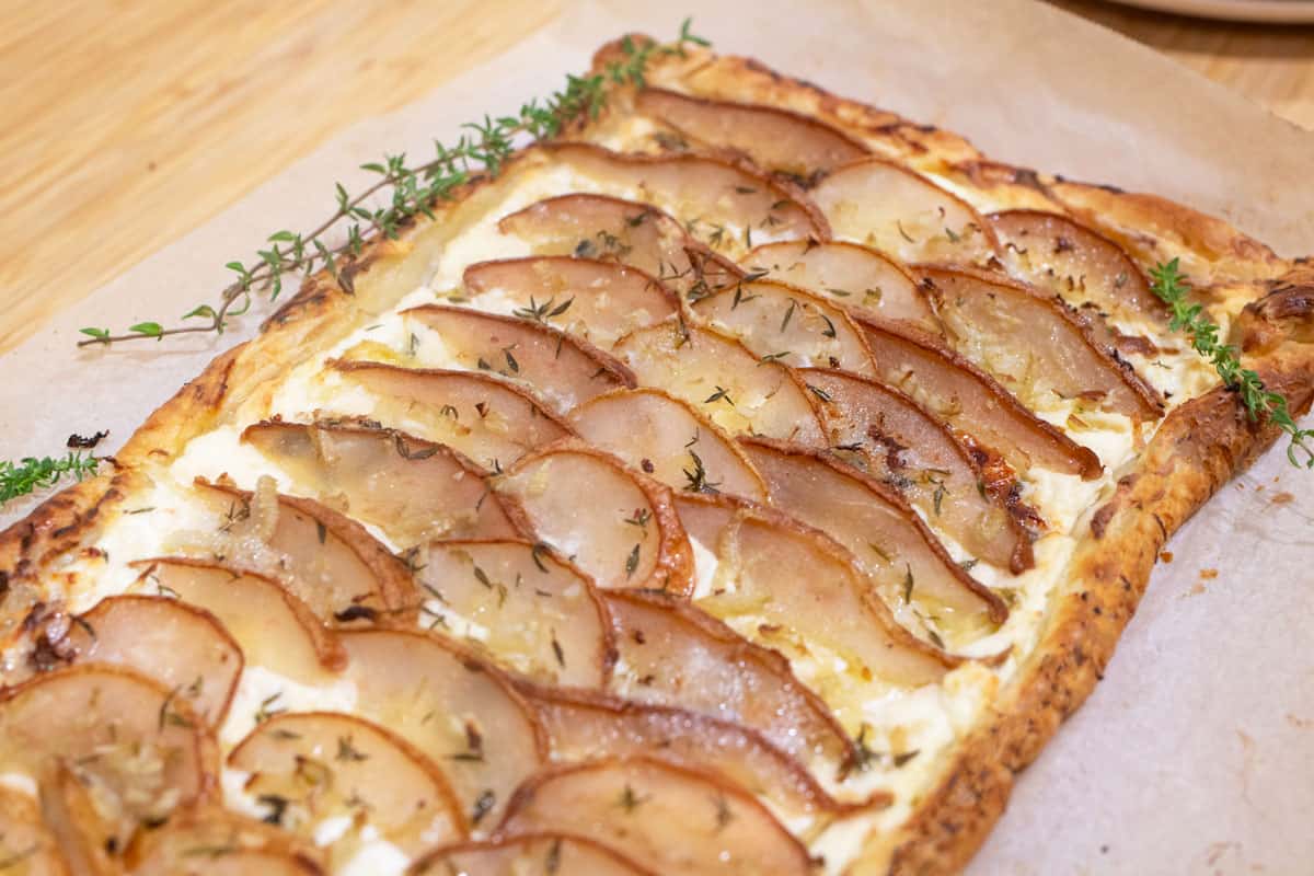 A blue cheese and pear tart with thyme on top.
