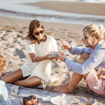Attractive couple enjoying a picnic with friends on the beach.
