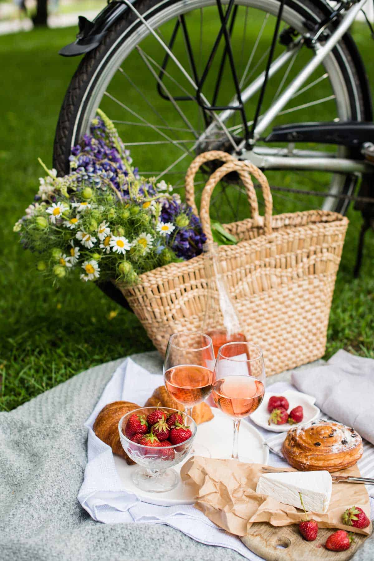 A spring picnic with flowers in a basket leaning against a bicycle. 