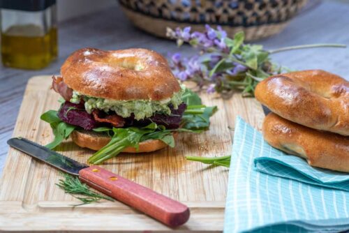 Bagel with beetroot and pea spread on a chopping board