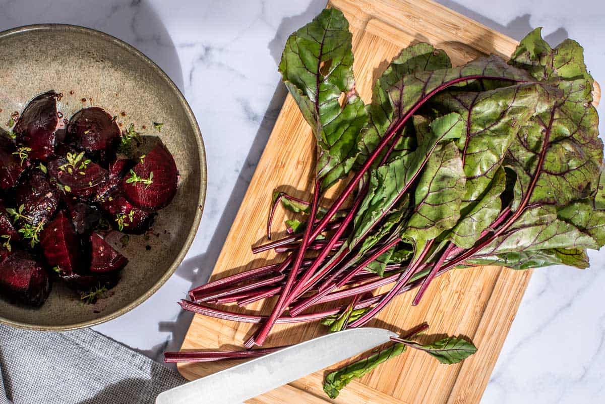 Beetroot leaves next to a bowl of roast beets.