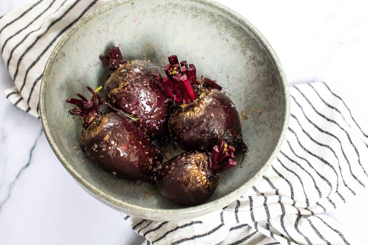 Bowl of raw beets dressed in oil and salt ready for roasting.