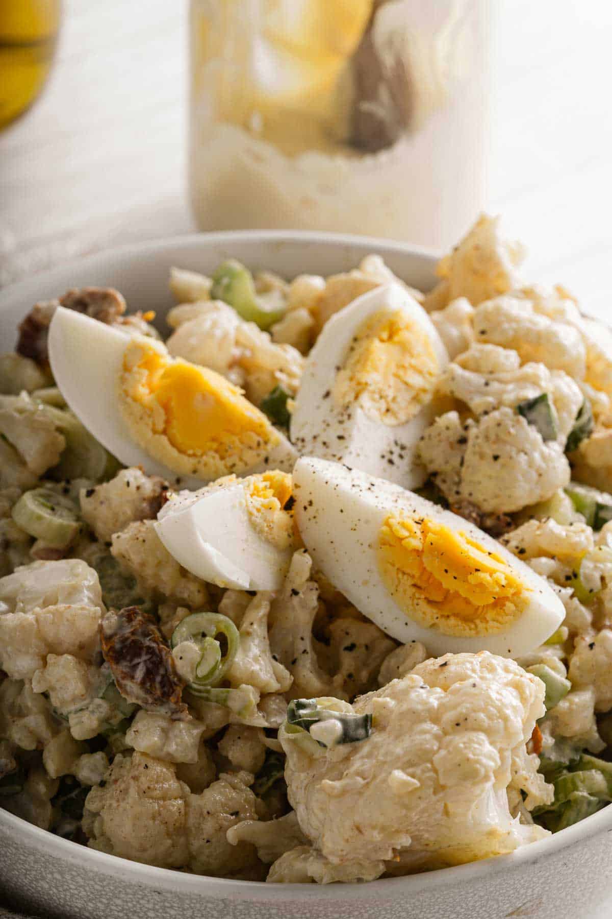A bowl of cauliflower salad with a hard boiled egg.