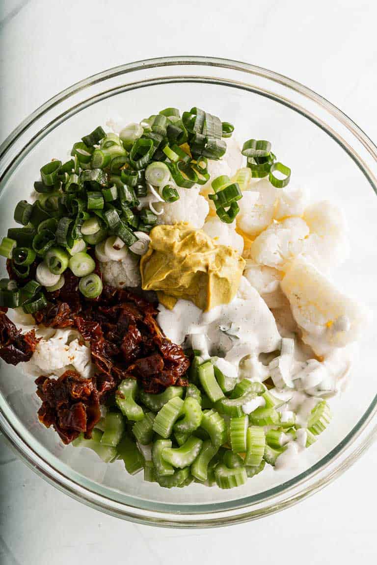Ingredients for cauliflower salad in a bowl before mixing.