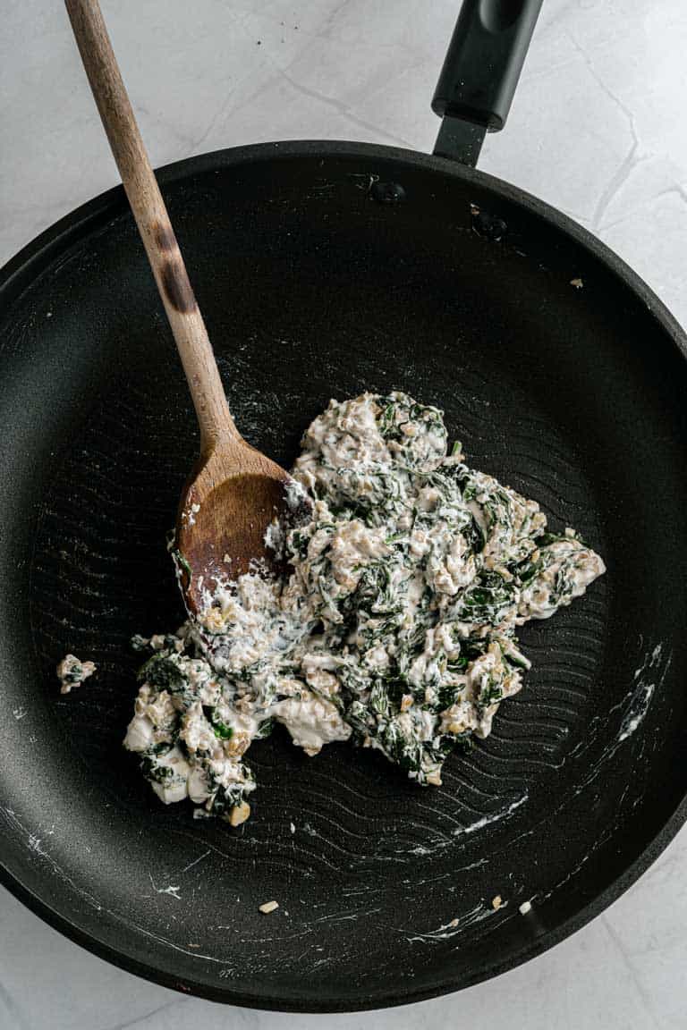 Cream cheese and spinach mix in a pan for stuffed mushrooms.