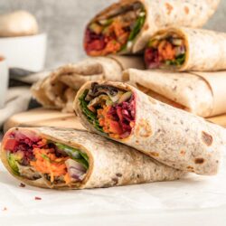 A stack of raw veggie wraps cut in half on a table