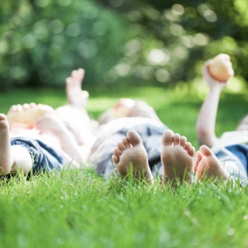 Kids lying on the grass with bare feet at a picnic.