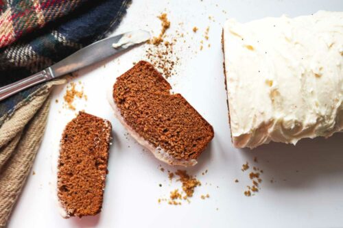 Slices of gingerbread loaf with cream cheese frosting.