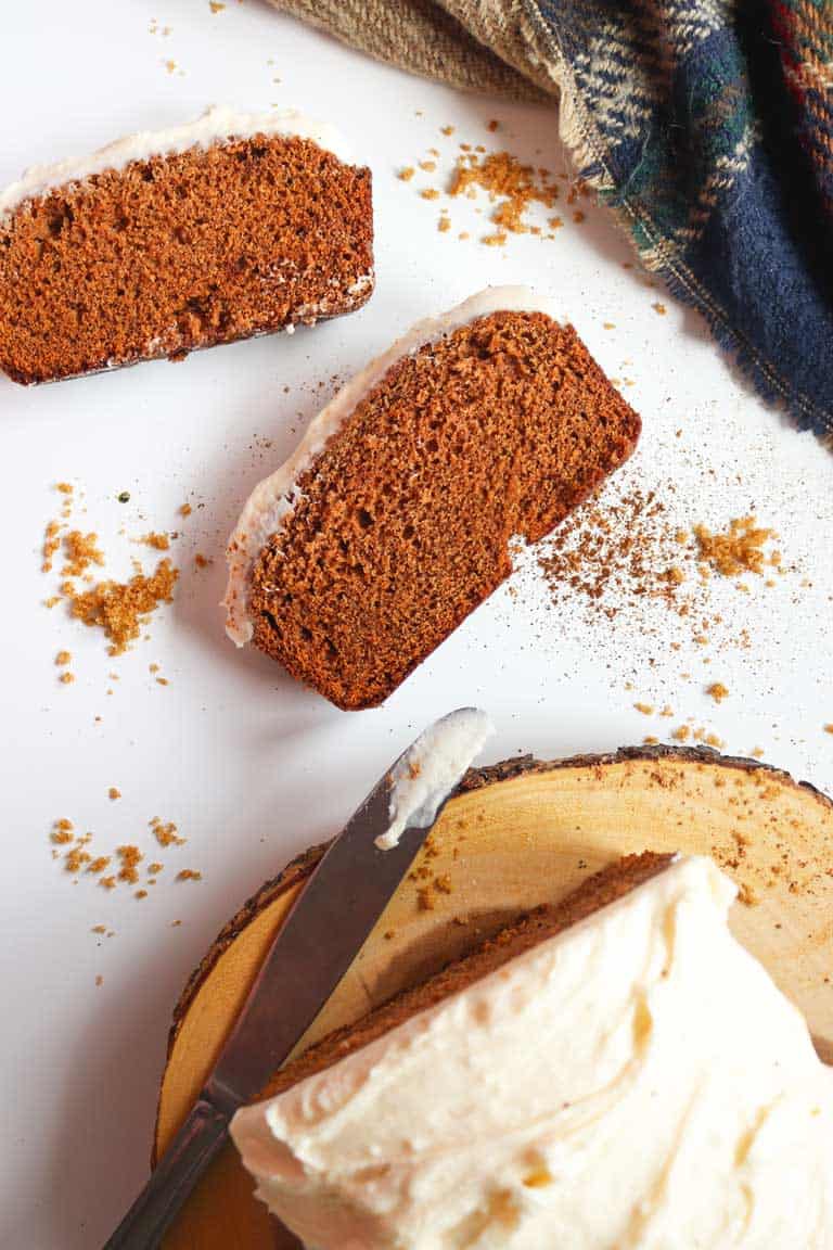 Gingerbread loaf cake cut into slices with thick cream cheese frosting. 