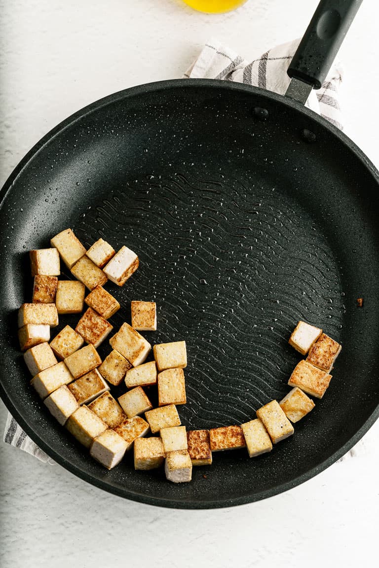 Cubed tofu cooking in a skillet pan.