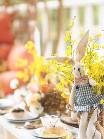 Stuffed Easter rabbit in a flower arrangement at an Easter picnic brunch setting.