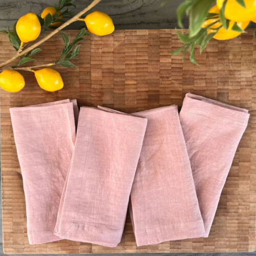 Four pink linen napkins on a cutting board.