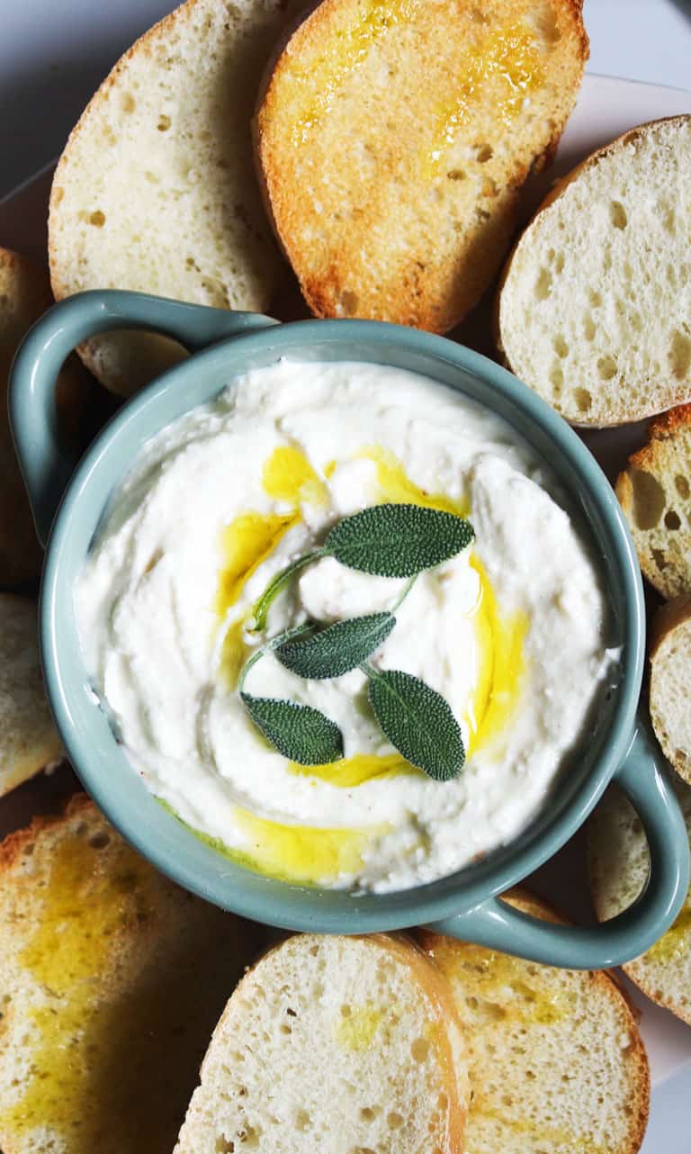 Bowl of whipped feta dip with bread slices.