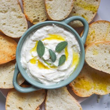 Bowl of whipped feta dip with bread slices.