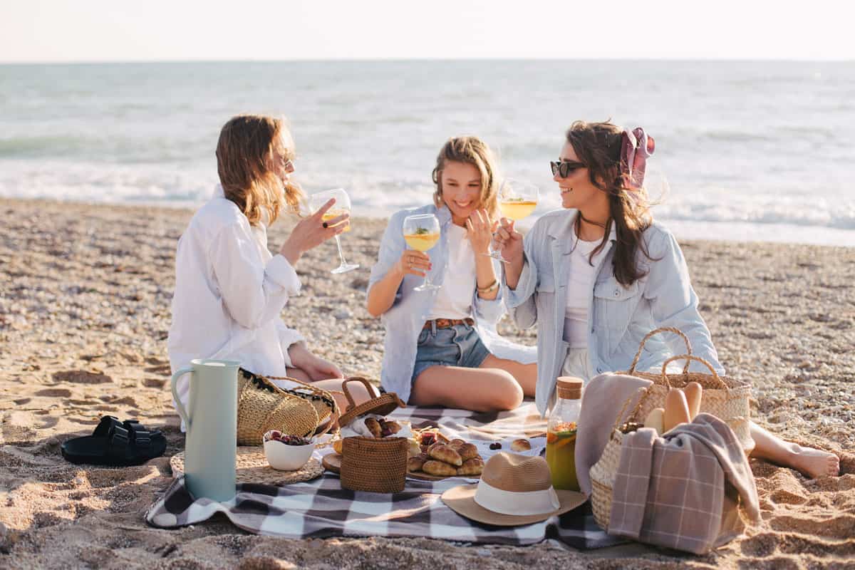 Three young women enjoying a brunch picnic on the beach.