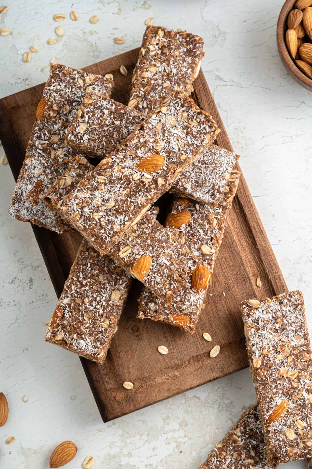 Chocolate oat bars on a wooden board sprinkled with nuts and coconut.