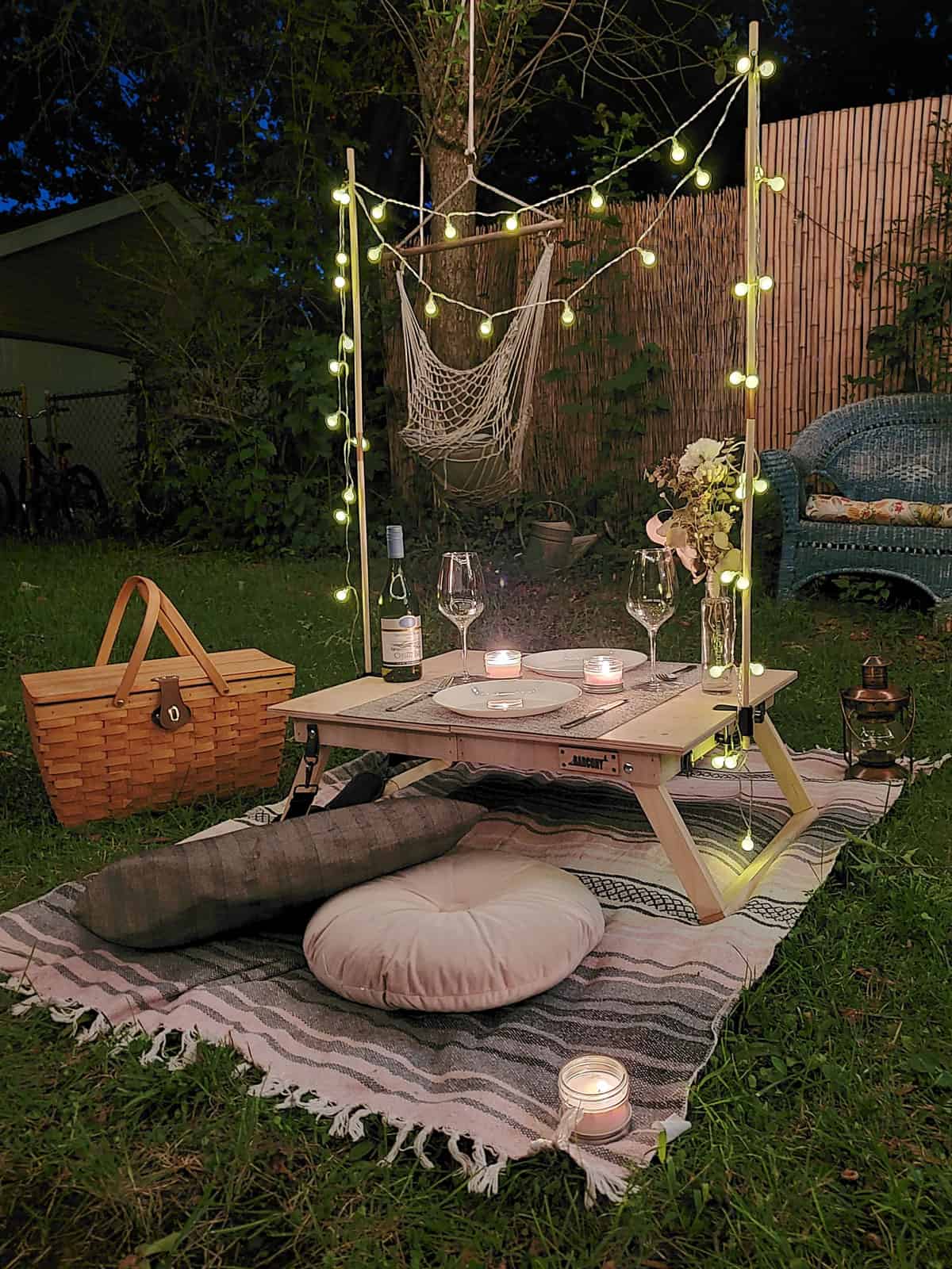 Romantic boho picnic setting at night with fairy lights.