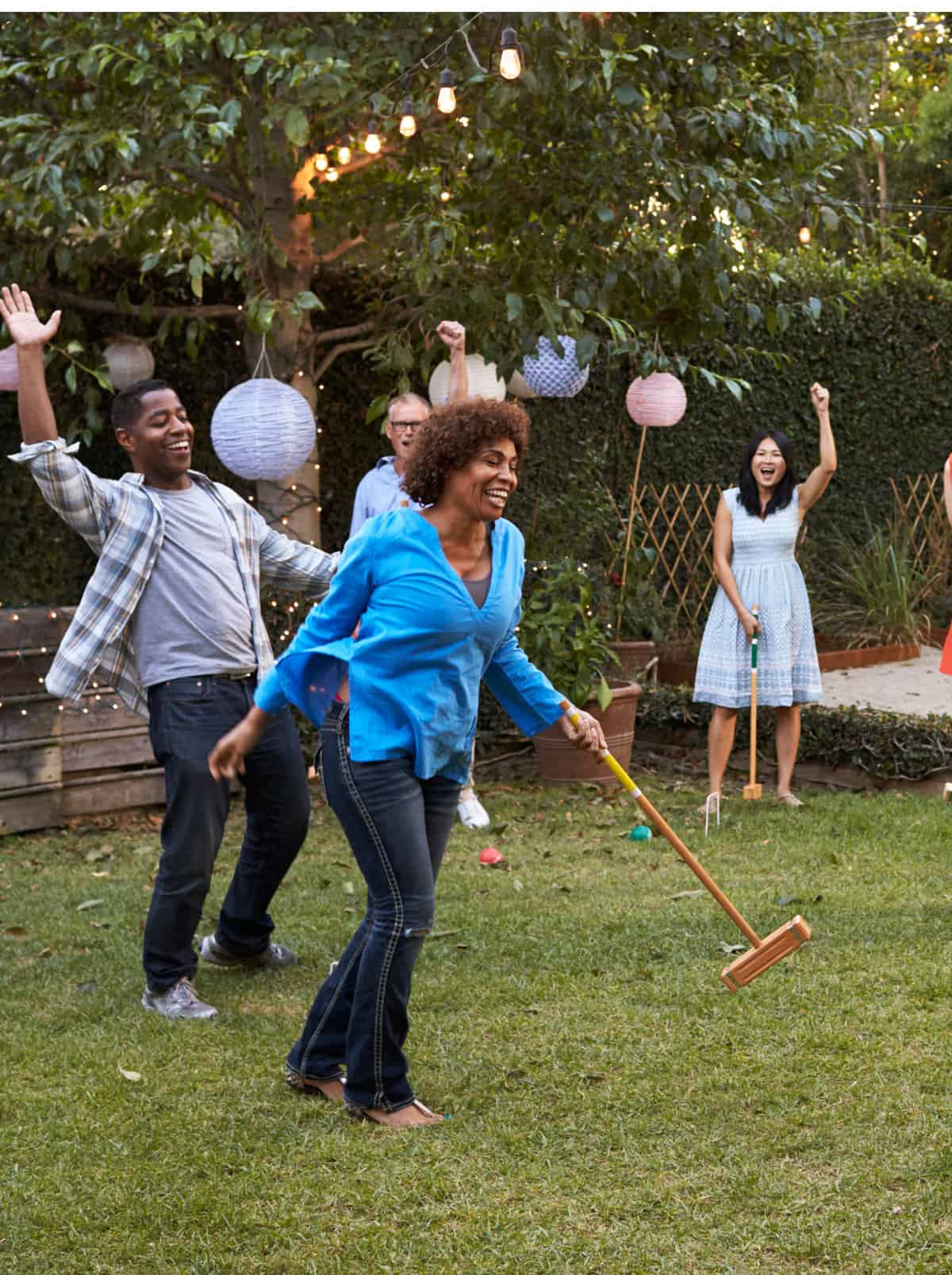 Adults playing croquet at a picnic. 